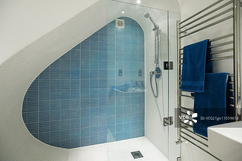 阁楼设计师淋浴房，配蓝色瓷砖和不锈钢毛巾架图片素材