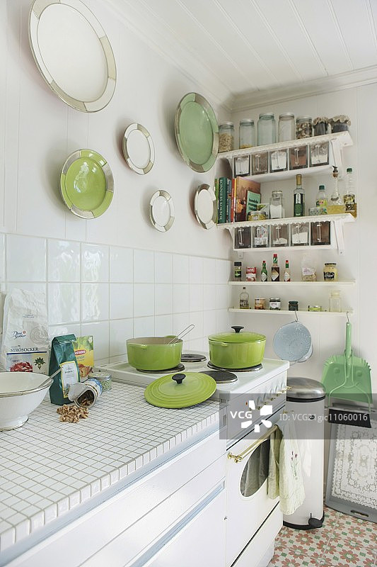 阳光明媚的厨房，配有复古灶具和墙上收集的白色和绿色瓷盘图片素材