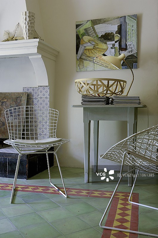 白色金属网椅和乡村风格控制台，位于客厅开放式壁炉旁的绿色瓷砖地板上图片素材