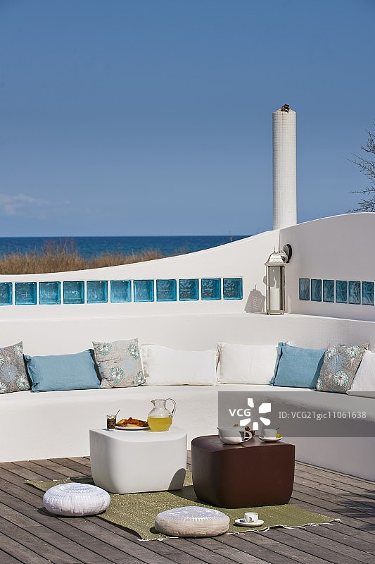 阳光明媚的屋顶露台，砖砌长椅和落地垫，旁边是边桌图片素材