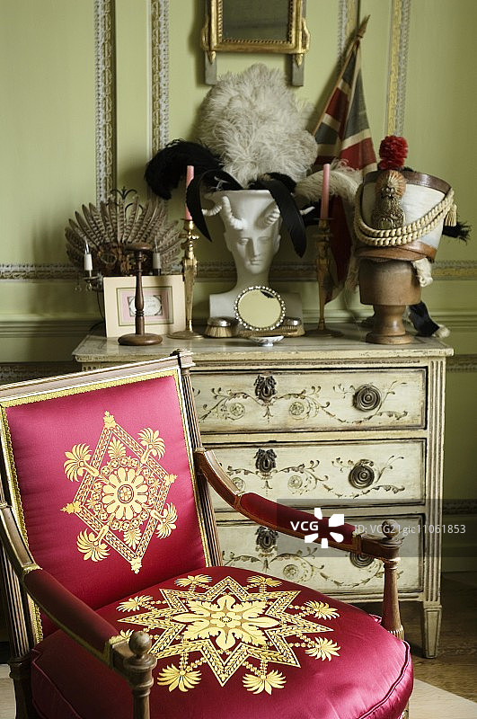 巴洛克风格的木椅，闪亮的红色软垫，金色图案，前面是彩绘的抽屉柜图片素材