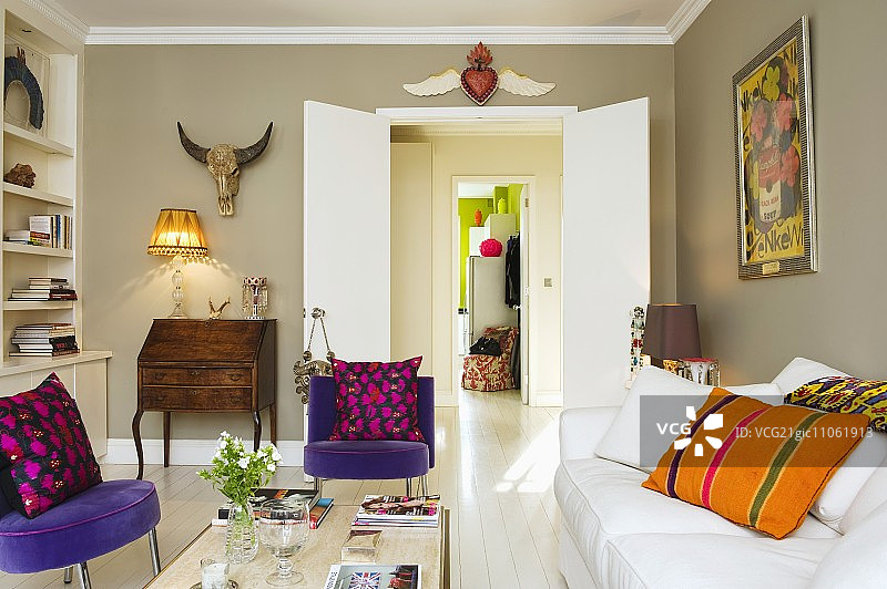 紫色丝绒椅和白色沙发，搭配彩色靠垫，正对着可通往衣帽间的双开门图片素材