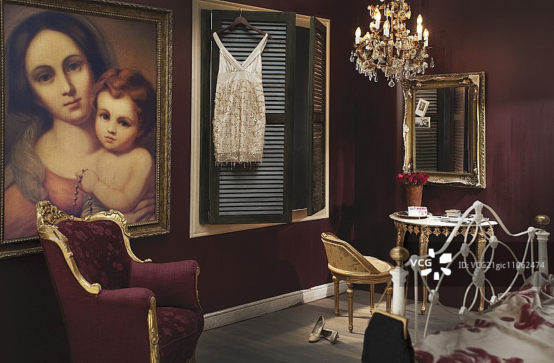 巴洛克时期家具、枝形吊灯和大尺幅麦当娜油画的卧室，深红色墙壁图片素材