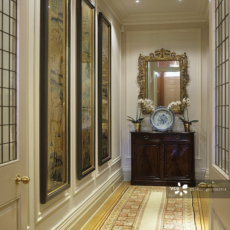 庄园走廊里，半高的古董柜子上，镀金镜子下方的装饰盘图片素材