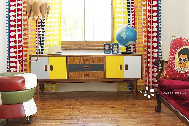 窗户下翻新的20世纪50年代餐具柜，配有色彩鲜艳的图案窗帘图片素材