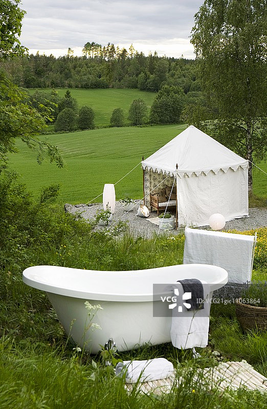复古浴缸在山坡上与绿色草地凉亭图片素材