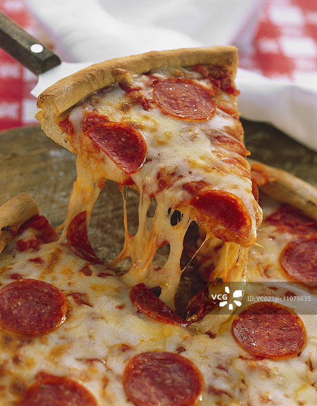 拿起的一片意大利辣香肠披萨图片素材