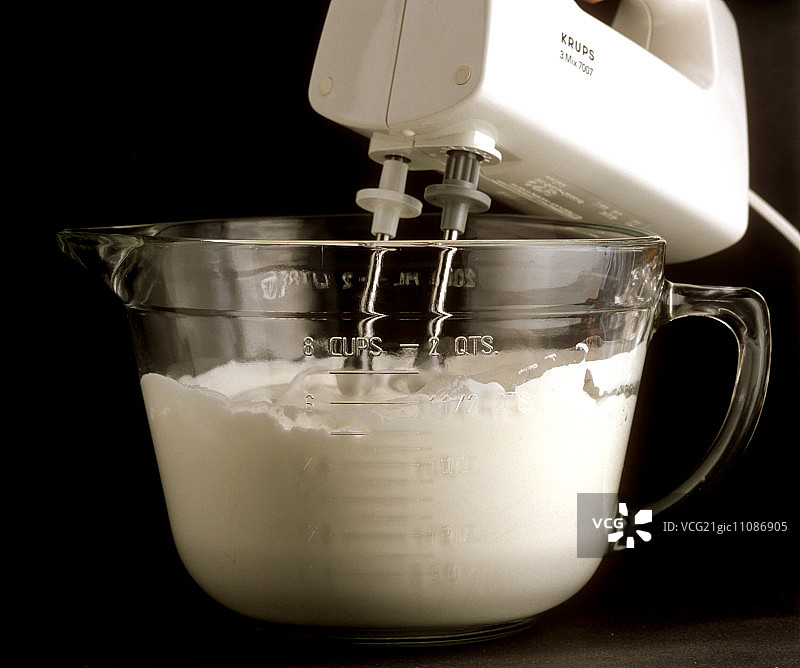 在黑色背景下用搅拌机搅打奶油图片素材