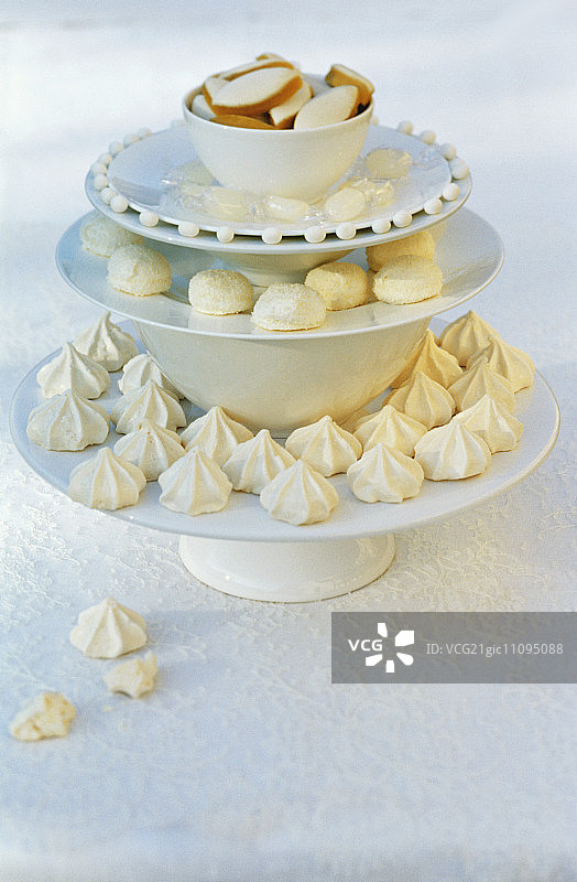 由堆叠的陶器组成的蛋糕架上的白色小蛋糕图片素材