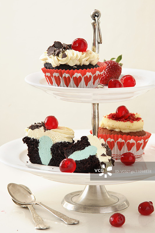 多层蛋糕架上的纸杯蛋糕：黑森林和红色天鹅绒纸杯蛋糕图片素材