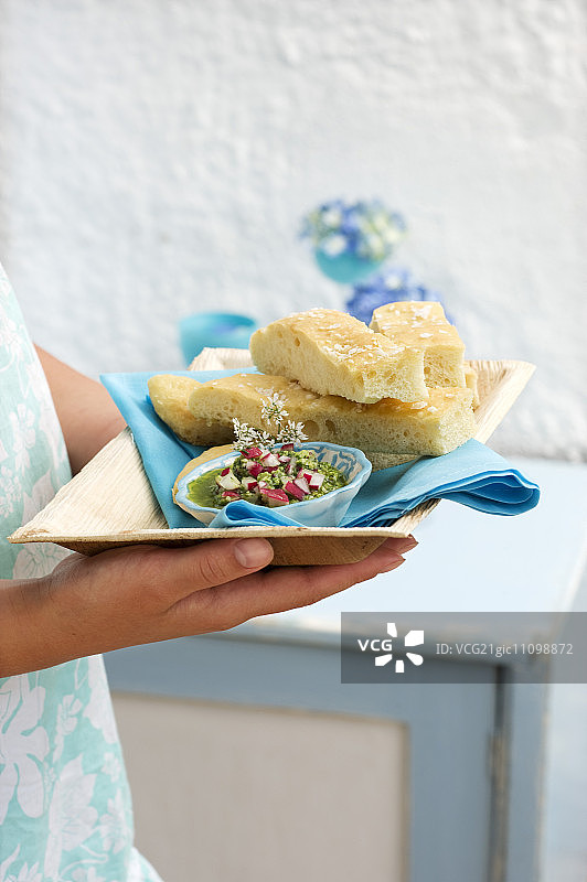 一位妇女在托盘上供应佛卡夏和萝卜叶蘸酱图片素材