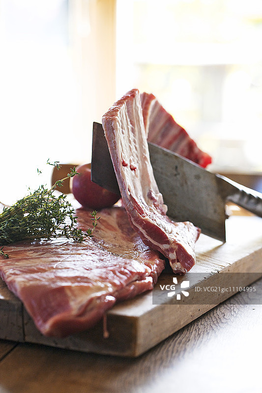木板上的生猪肋排和肉刀图片素材