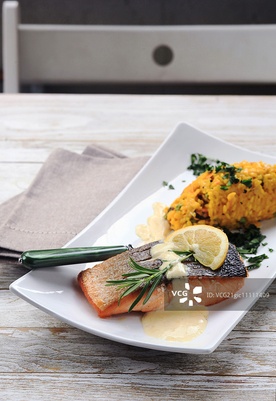 烤三文鱼配迷迭香柠檬酱和黄色烩饭图片素材