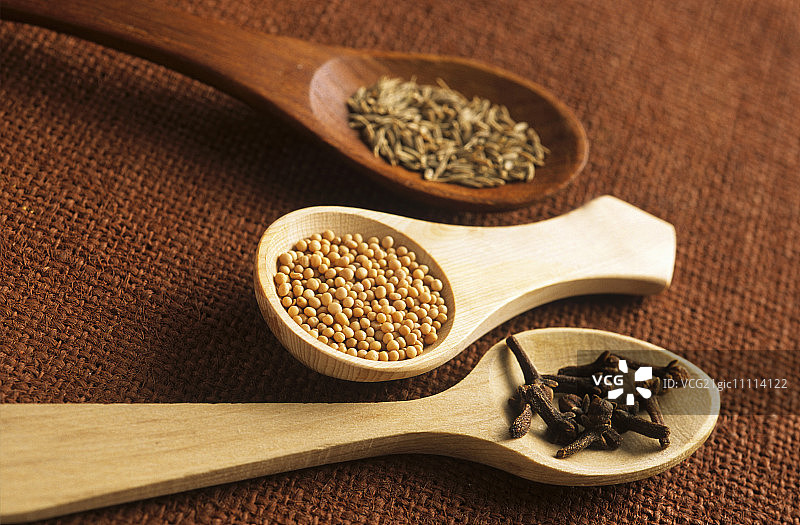 盛放芥菜籽、香芹籽和丁香的木勺图片素材