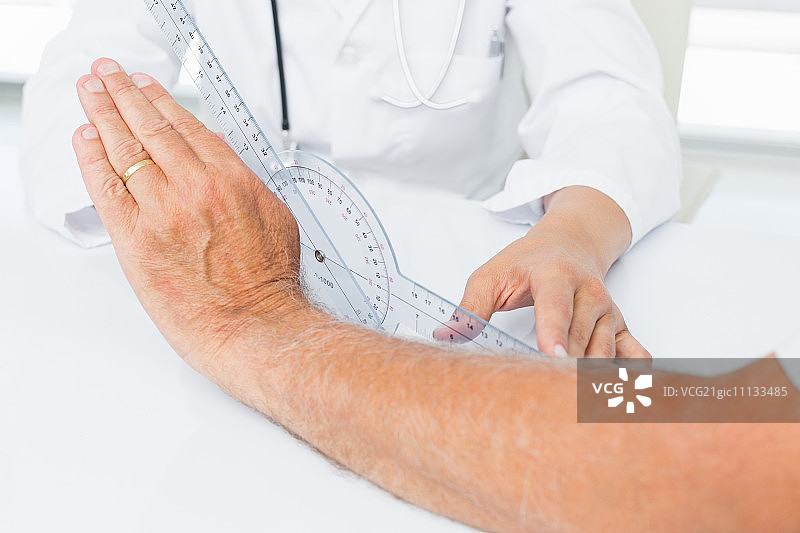 理疗师用测角器检查病人手腕的中部特写图片素材