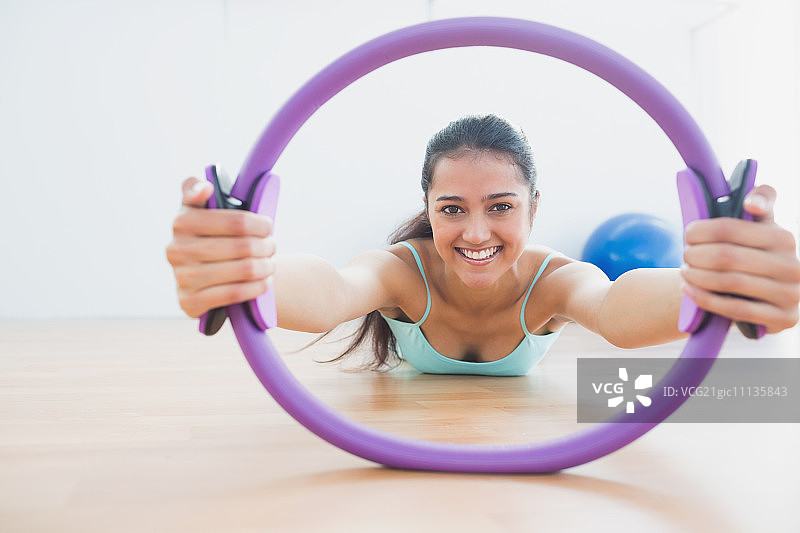 健身房里拿着健身圈的笑容满面的运动型年轻女人图片素材