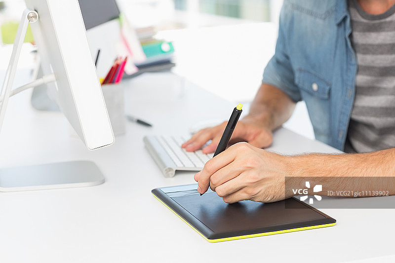 休闲男照片编辑在明亮办公室使用绘图板的中部特写图片素材