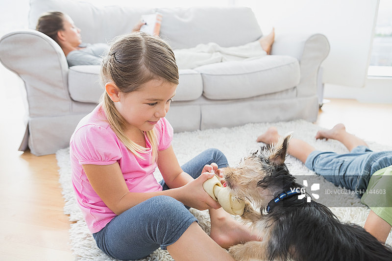 兄弟姐妹和约克夏犬一起躺在客厅的地毯上图片素材