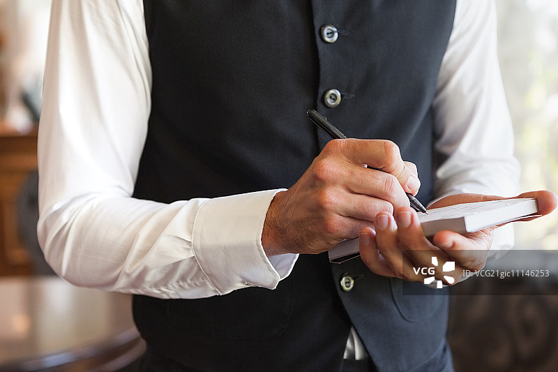 服务员在高级餐厅身穿马甲点餐图片素材