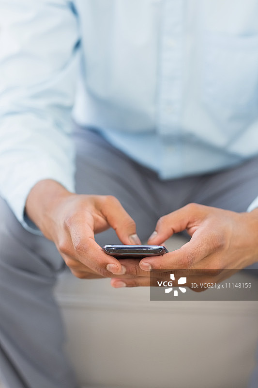 在办公室沙发上发短信的男人图片素材