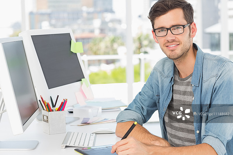 明亮办公室里，使用绘图板的休闲男性照片编辑师肖像图片素材
