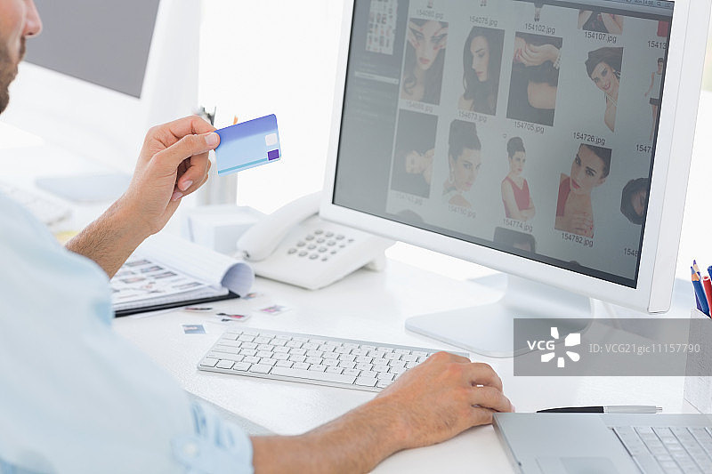 男性照片编辑在明亮办公室里使用电脑的侧视图图片素材