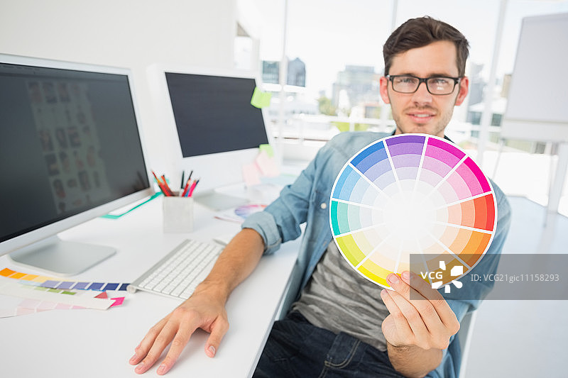 男艺术家在办公桌旁拿着色轮图片素材