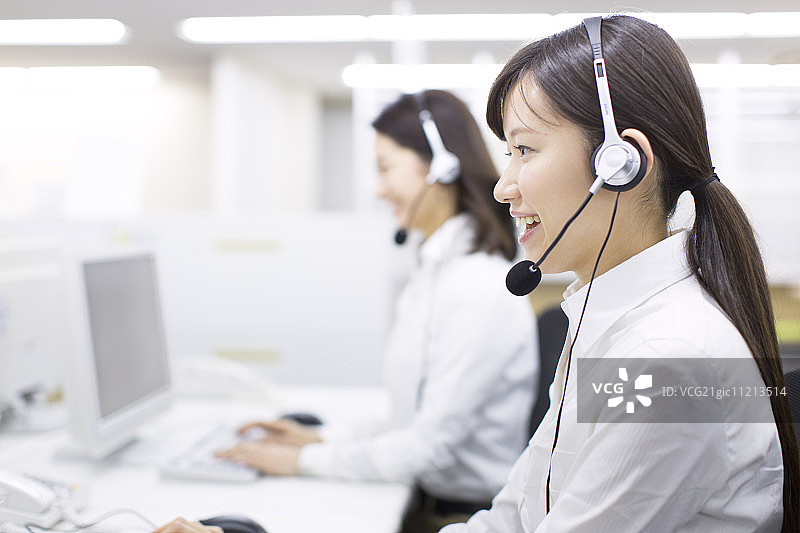 在呼叫中心戴着耳机的年轻女商人图片素材