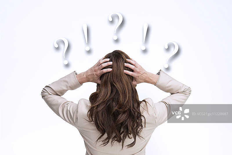年轻优雅的商务女性，双手抱头，背对镜头，背景为问号和感叹号图片素材