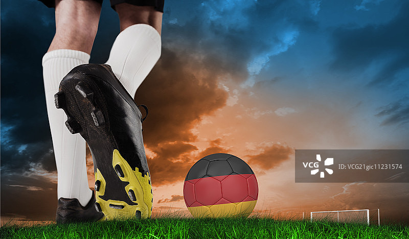 足球鞋踢德国足球合成图像（绿草蓝天背景）图片素材