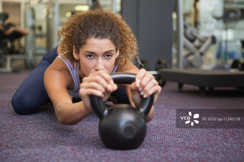 身材好的女人躺在健身房的壶铃旁。图片素材