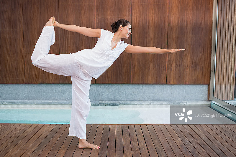 在水疗中心摆出湿婆姿势的白衣棕发女子图片素材