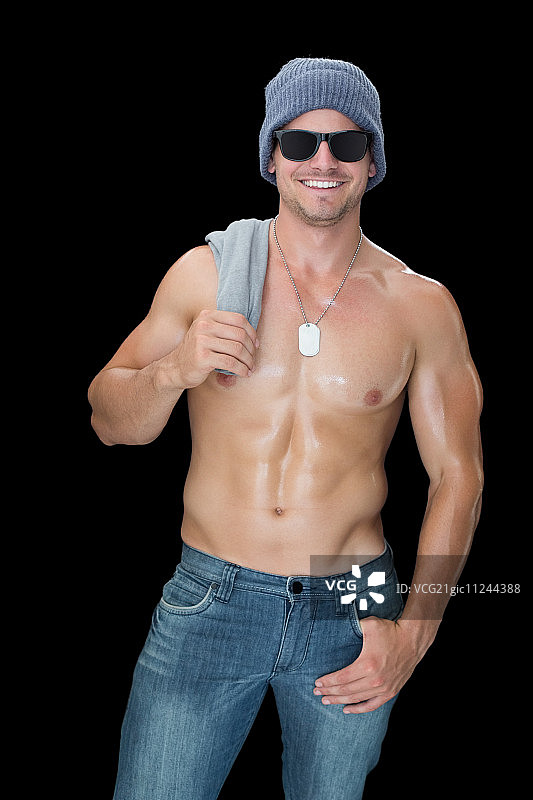 戴着蓝色牛仔帽和太阳镜在黑色背景前摆姿势的健壮男人图片素材