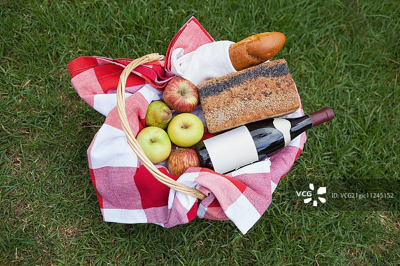 草地上装有红酒和面包的野餐篮图片素材