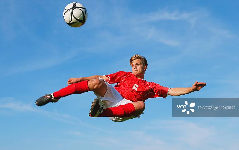 半空中踢球的足球运动员图片素材