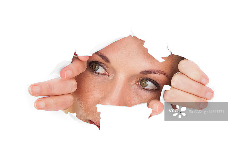 透过白色背景上撕裂的纸张向外看的女人图片素材