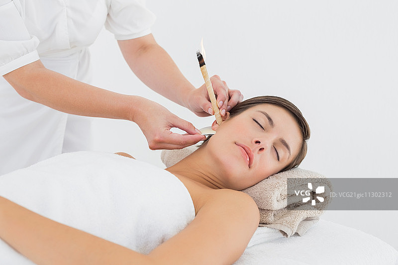 年轻美女在水疗中心接受耳烛护理特写图片素材