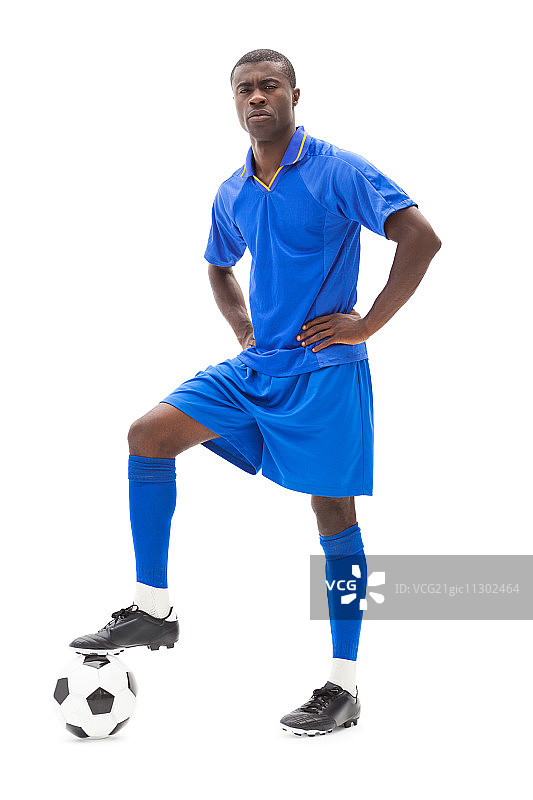 蓝色球衣的足球运动员在白色背景上持球站立图片素材
