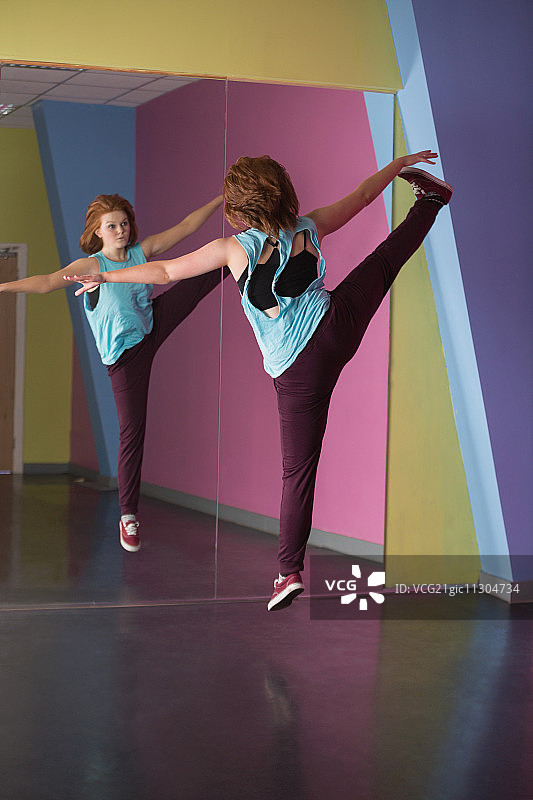 在舞蹈工作室里跳跃并照镜子的漂亮霹雳舞者图片素材