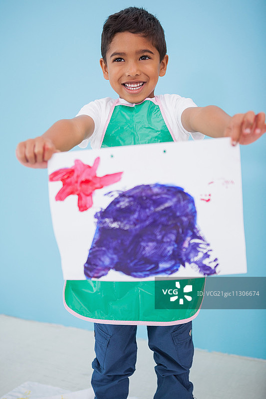 可爱的小男孩在幼儿园的教室里展示他的画图片素材