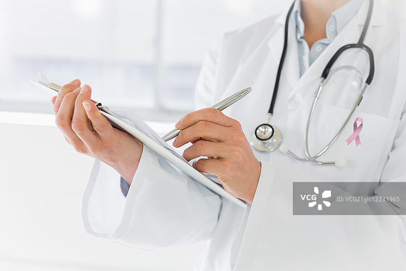 佩戴乳腺癌宣传丝带撰写报告的女医生中部特写图片素材
