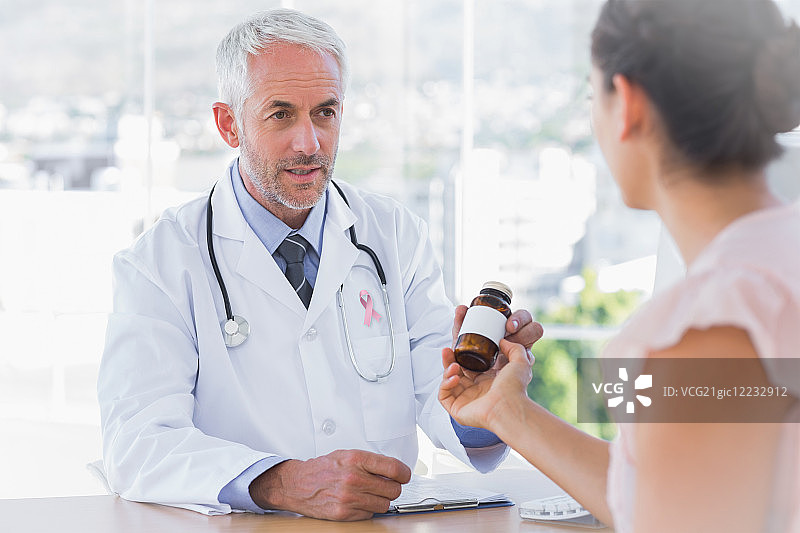 病人拿着药罐，佩戴乳腺癌防治宣传丝带图片素材