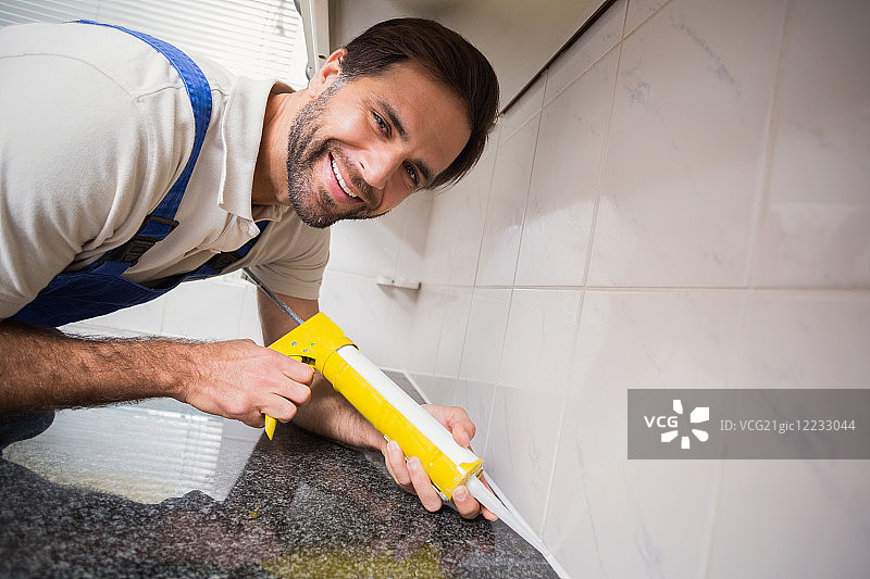 水管工在厨房瓷砖之间填充图片素材