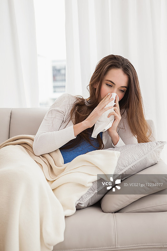 生病的棕发女人躺在客厅的沙发上图片素材