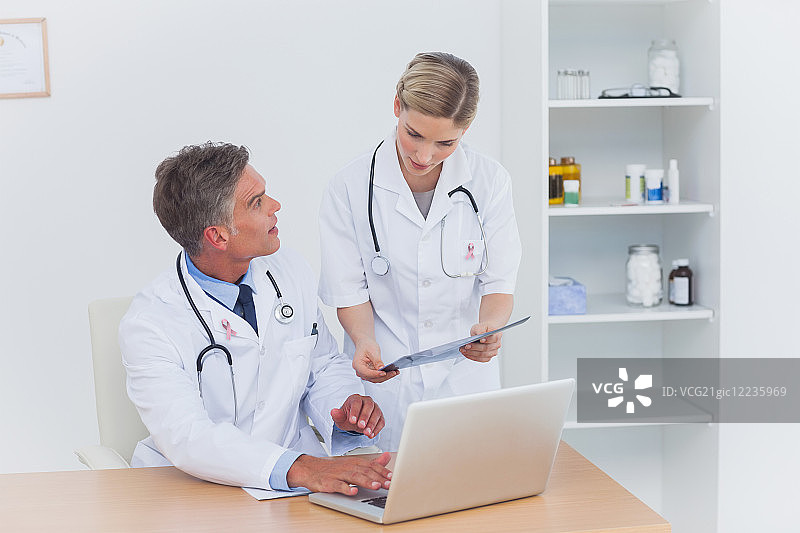 护士向佩戴乳腺癌意识丝带的同事展示文件夹图片素材