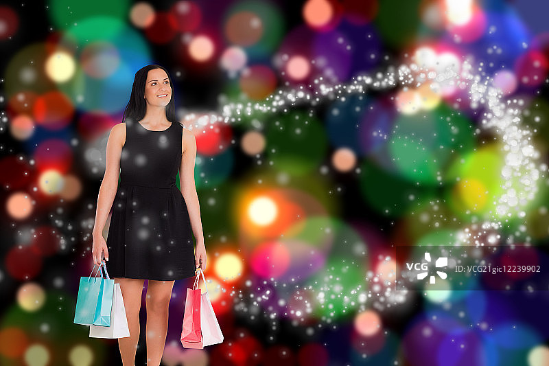 手提购物袋走在灯光模糊背景下的女人图片素材