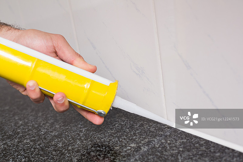 水管工在厨房瓷砖之间填充图片素材