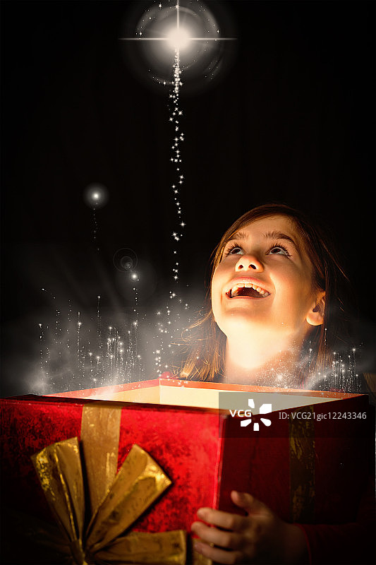 小女孩在雪中打开神奇的圣诞礼物图片素材