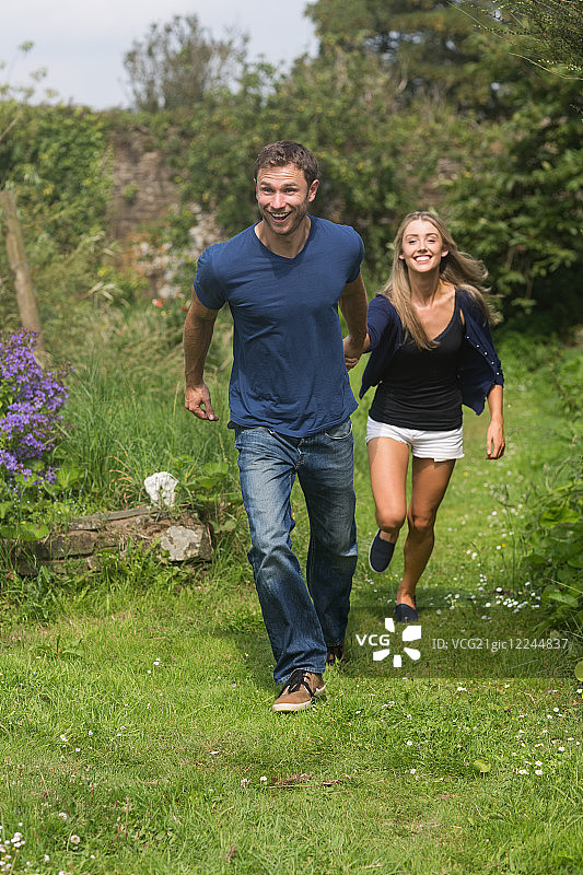 情侣在花园里手牵手奔跑，充满活力图片素材