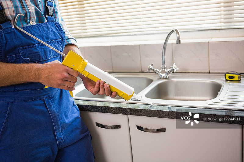 水管工在厨房瓷砖之间填充图片素材